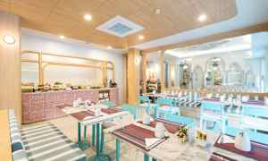 Vaalea ja moderni aamiaistila, jossa pöytiä, sinisiä tuoleja ja buffetalue. (Tekoälyn luoma teksti)