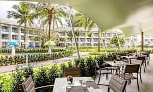 Ravintola ulkoterassilla puutarhan lähellä, jossa on nurmialue ja leikkipaikka. (Tekoälyn luoma teksti)