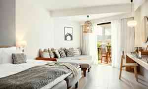 Valoisa ja moderni hotellihuone, jossa sänky, istuimet ja parvekkeenaukeama. (Tekoälyn luoma teksti)