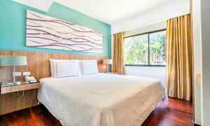 Hotellihuone, jossa on parivuode, suuret ikkunat ja verhot. (Tekoälyn luoma teksti)