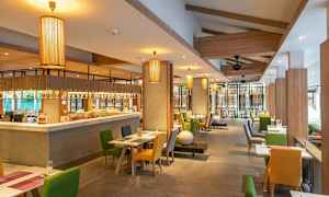 Ravintolan sisätilat, joissa pöydät ja tuolit eri väreissä sekä riippuvalaisimet. (Tekoälyn luoma teksti)