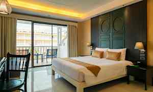 Hotellihuone, jossa on suuri sänky, työpöytä ja parveke, jossa on tuoleja. (Tekoälyn luoma teksti)