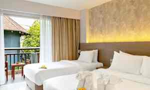 Kaksi pedattua yhden hengen sänkyä koristeellisilla pyyhkeillä ja kukilla. Näkymä kalustetulle parvekkeelle, jossa vihreää ja rakennus. (Tekoälyn luoma teksti)