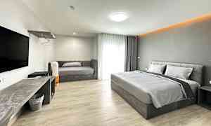 Hotellihuone, jossa on parivuode, sohva ja seinälle asennettu televisio. (Tekoälyn luoma teksti)