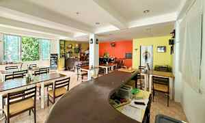 Kuva sisätilasta, jossa on pöytiä, tuoleja ja värikkäät seinät. (Tekoälyn luoma teksti)