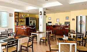 Kuva pienestä ravintolasta tai kahvilasta, jossa on pöytiä ja tuoleja, baaritiski sekä sisustus, joka sisältää koriste-esineitä ja koristeita. (Tekoälyn luoma teksti)