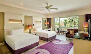 Hotellihuone kahdella sängyllä, istuma-alueella ja näkymällä vihreään lasiovesta. (Tekoälyn luoma teksti)