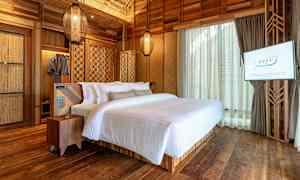 Makuuuhuone, jossa on parivuode valkoisilla vuodevaatteilla, puuseinät ja puulattia. TV on asennettu seinälle. (Tekoälyn luoma teksti)