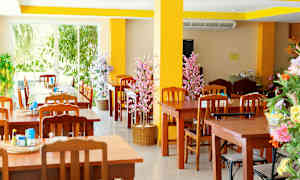 Ravintola, jossa puisia pöytiä ja tuoleja sekä koristeellisia kukkia. (Tekoälyn luoma teksti)