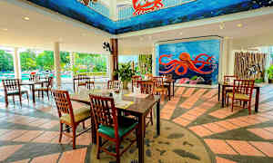 Ravintola puisilla kalusteilla, värikkäitä seinämaalauksia meri-teemalla, ja uima-allas taustalla. (Tekoälyn luoma teksti)