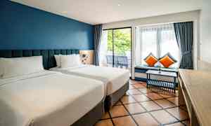 Kaksi yhden hengen vuodetta hotellihuoneessa, jossa on siniset seinät ja suuret ikkunat. (Tekoälyn luoma teksti)