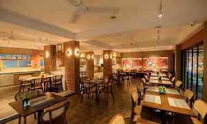 Ravintolassa on puisia pöytiä ja tuoleja, koristeltuna punaisilla seinillä ja taideteoksilla. (Tekoälyn luoma teksti)