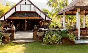 Avoin ravintola perinteisessä rakennuksessa vihreässä ympäristössä. (Tekoälyn luoma teksti)