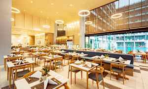 Kuva ravintolasta, jossa on aseteltuja pöytiä ja tuoleja modernissa ympäristössä. (Tekoälyn luoma teksti)