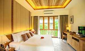 Makuuhuone, jossa on suuri parivuode, koristeelliset tyynyt ja yövalo. Suuri ikkuna verhoineen tuo sisään luonnonvaloa. (Tekoälyn luoma teksti)