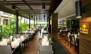 Ravintola ulkoterassilla, sisustettu rottinkituoleilla ja pöydillä, jotka on katettu liinoilla ja laseilla. (Tekoälyn luoma teksti)