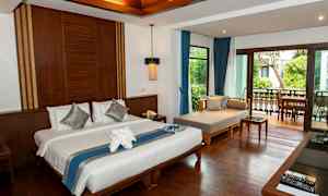 Hotellihuone, jossa pedattu sänky, oleskelualue ja parveke, josta näkyy kasvillisuutta. (Tekoälyn luoma teksti)