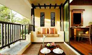 Terassi, jossa sohva koristeltu tyynyillä, pieni pöytä hedelmineen ja lautasiineen sekä näkymä vehreyteen. (Tekoälyn luoma teksti)