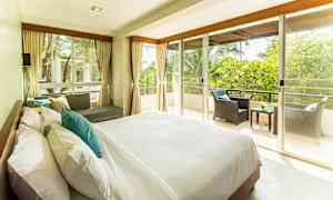 Valoisa ja tilava makuuhuone, jossa suuri sänky, sohvaryhmä ja parveke näköalalla vehreyteen. (Tekoälyn luoma teksti)