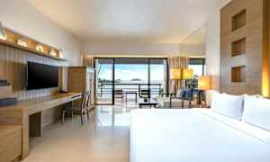 Hotellihuone, jossa on parivuode, työpöytä ja televisio sekä näkymä merelle suuren lasioven kautta, joka johtaa parvekkeelle. (Tekoälyn luoma teksti)