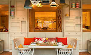 Pöytä kattausten kanssa seisoo sohvan ja kahden tuolin edessä ulkoterassilla koristeellisten lamppujen alla. (Tekoälyn luoma teksti)