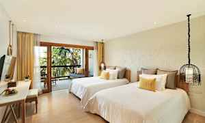 Hotellihuone, jossa on kaksi erillistä vuodetta, parveke näkymällä palmuihin ja istuinnurkkaus. (Tekoälyn luoma teksti)