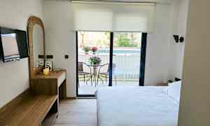 Hotellihuone, jossa on parivuode, kirjoituspöytä, televisio ja parveke puutarhakalusteilla. (Tekoälyn luoma teksti)