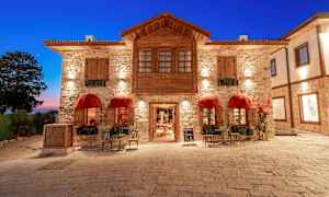 Kivirakennus, jossa on punaiset markiisit ja istuimia kivetyllä torilla. (Tekoälyn luoma teksti)