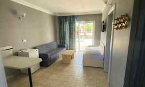 Hotellihuone, jossa on sohva, pöytä ja sänky, sekä näkymä parvekkeelle. (Tekoälyn luoma teksti)