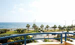 Näkymä parvekkeelta rannikkolinjalle, jossa palmuja ja meri. (Tekoälyn luoma teksti)