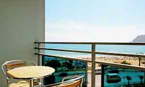 Parveke, jossa pöytä ja kaksi tuolia, näkymä rannalle ja merelle. (Tekoälyn luoma teksti)