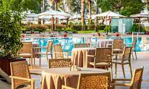 Ulkotila, jossa istuinryhmät ja ruokapöydät altaan vieressä. (Tekoälyn luoma teksti)