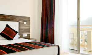 Hotellihuone, jossa yksittäinen sänky ja parveke näkymällä. (Tekoälyn luoma teksti)