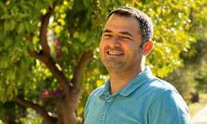 Henkilö sinisessä paidassa seisoo vehreän puutarhan edessä. (Tekoälyn luoma teksti)