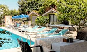 Ulkoallas aurinkotuolien, pöytien ja tuolien vieressä pienten rakennusten lähellä. (Tekoälyn luoma teksti)