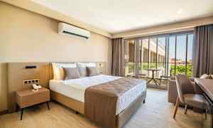 Hotellihuone, jossa suuri sänky, pieni pöytä ja parveke näkymällä. (Tekoälyn luoma teksti)