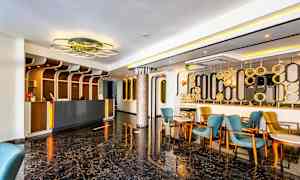 Aula vastaanotolla, sinisiä ja keltaisia tuoleja sekä moderni sisustus. (Tekoälyn luoma teksti)