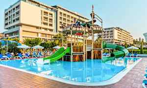 Ulkouima-allasalue, jossa on leikkipaikka vihreillä liukumäillä, ja lähellä oleva hotelli. (Tekoälyn luoma teksti)