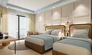 Hotellihuone, jossa kaksi yhden hengen vuodetta, vaalea sisustus ja ikkunat verhoilla. (Tekoälyn luoma teksti)