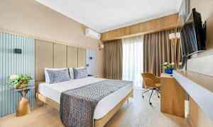 Kuva hotellihuoneesta, jossa on parisänky, kirjoituspöytä, tuoli ja televisio. (Tekoälyn luoma teksti)