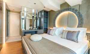 Moderni hotellihuone, jossa sänky, työpöytä ja koristeellinen valaistus. (Tekoälyn luoma teksti)