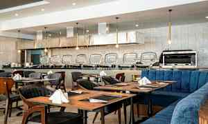 Ravintola, jossa katettuja pöytiä ja buffetpöytä taustalla. (Tekoälyn luoma teksti)