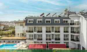 Hotelli, jossa on valkoinen julkisivu ja useita ikkunoita ja parvekkeita, uima-allas rakennuksen edessä. (Tekoälyn luoma teksti)