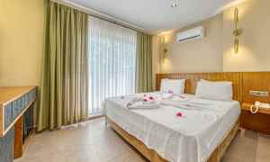 Hotellihuone, jossa on parivuode pedattu valkoisilla lakanoilla ja koristeltu kukilla. (Tekoälyn luoma teksti)