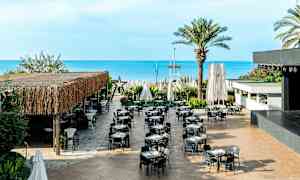 Ulkona sijaitseva ravintola, jossa on pöytiä ja tuoleja, meren lähellä. (Tekoälyn luoma teksti)