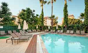 Ulkouima-allas hotelliympäristössä, ympärillä aurinkotuoleja ja aurinkovarjoja. (Tekoälyn luoma teksti)