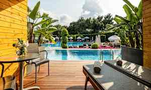 Terassi uima-altaan edessä, jossa on aurinkotuoleja, pöytä ja kasveja. (Tekoälyn luoma teksti)