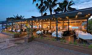 Rantaravintola, jossa on valkoisia pöytäliinoja iltavalaistuksessa. (Tekoälyn luoma teksti)