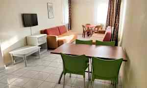 Olohuone, jossa on sohvia, ruokapöytä tuoleineen ja seinälle kiinnitetty televisio. (Tekoälyn luoma teksti)