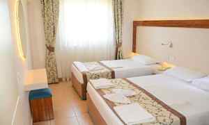 Hotellihuone, jossa kaksi erillistä sänkyä, vaaleat verhot ja peili. (Tekoälyn luoma teksti)